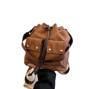 Brown nylon drawstring bucket bag with side pockets and adjustable crossbody strap