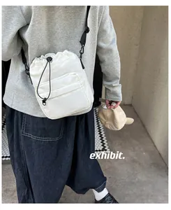 Detail of white nylon bucket bag with drawstring closure and black adjustable strap