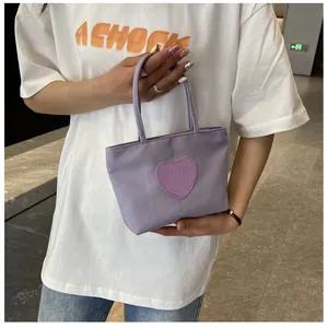 Detail of a purple nylon mini handbag featuring a heart-shaped smiley face patch