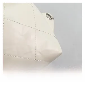 Close-up of white quilted leather texture and silver metal eyelet on a designer handbag