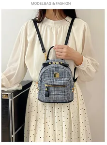 Close-up of a blue tweed mini backpack with black leather bow and gold zipper details