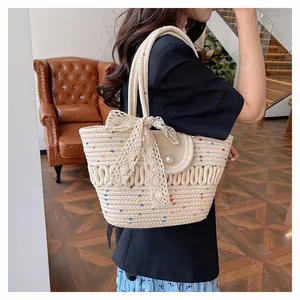 Détail du sac seau en paille avec nœud en dentelle, broderie et fermoir perle