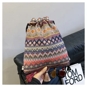 Dettaglio ravvicinato della borsa boho intrecciata con motivi geometrici e lunghe nappe