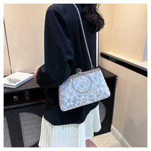 Silver sequin evening clutch with ring handle and metal chain on a model in a black suit