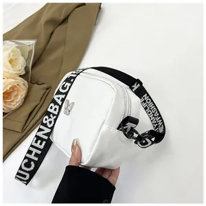 Détail du sac bandoulière blanc carré avec logo papillon argenté et bandoulière tissée