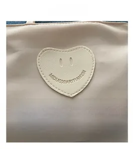 Close-up of beige nylon fabric featuring a heart-shaped faux leather patch with a smiley face