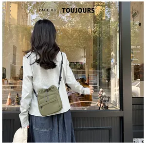 Detail view of olive green nylon drawstring crossbody bag worn over a grey sweatshirt