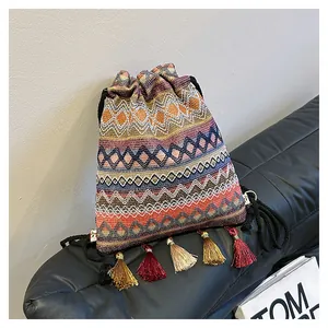 Dettaglio borsa a secchiello etnica intrecciata con nappe colorate e chiusura a coulisse