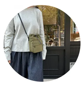 Detailed view of an olive green nylon drawstring bucket bag with an external zipper pocket