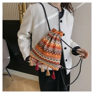 Dettaglio borsa bohémien con coulisse, motivi geometrici e nappine multicolore
