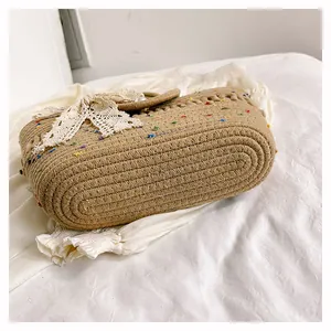 Détail d'un sac cabas tissé main avec nœud en dentelle sur un tissu blanc froissé