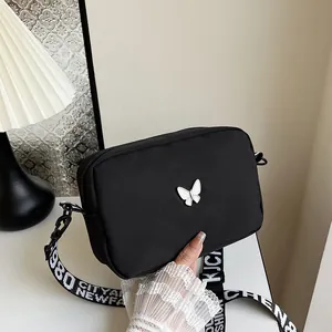 Petit sac carré noir en nylon avec décor papillon et bandoulière large lettrée