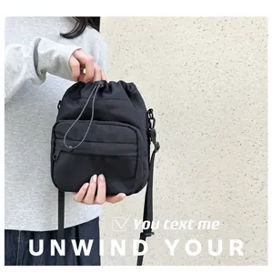 Detail of black nylon drawstring bucket bag showing adjustable strap and front pocket