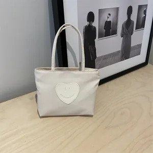 Cute beige nylon mini tote bag with heart smiley face patch on a wooden surface