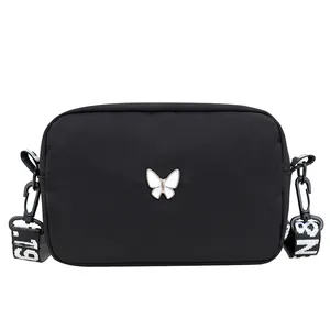 Sac bandoulière en nylon noir avec breloque papillon et large bandoulière décorée