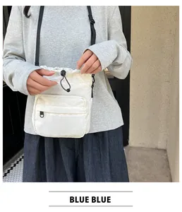 Detailed view of the white nylon bucket bag showing the drawstring closure and zipper pocket