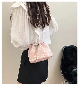 Detail of pink drawstring bucket bag with white 3D flower embroidery and pearl accents