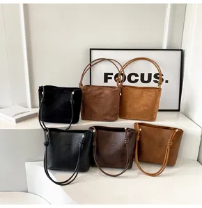Detailed view of minimalist suede bucket bags in multiple colors with knot shoulder straps