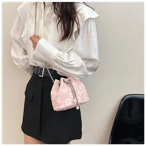 Detail of pink bucket bag with white floral pattern, pearl charms and metal chain strap