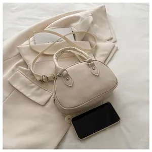 Dettaglio della borsa a tracolla minimalista in similpelle crema con hardware argentato