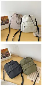 Detail view of nylon drawstring bucket bags in beige, white, black, and army green