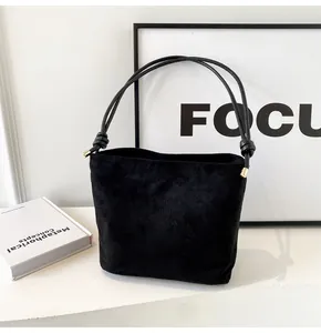 Detail of black suede bucket bag with Fashion and Sunday embossed text and gold hardware