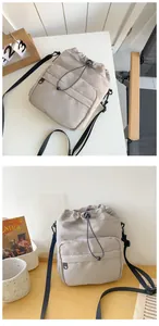 Detail of light grey nylon drawstring bucket bag with adjustable black shoulder strap