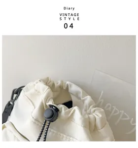 Detail of white nylon bucket bag featuring adjustable drawstring and black hardware accents