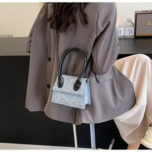 Detalle del bolso bandolera azul grisáceo claro con asas negras y logo metálico JINGPIN