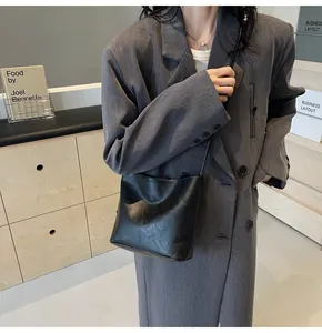 Close-up of minimalist black suede bucket bag with fashion and Sunday embossed text