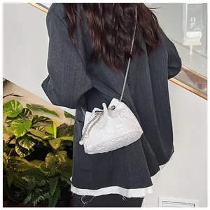 Detailed view of white jacquard bucket bag with floral texture and pearl chain strap