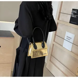 Detalle de bolso bandolera dorado metalizado con asa negra y logo JINGPIN grabado