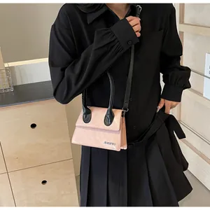 Bolso bandolera rosa y negro con logo JINGPIN llevado por modelo en ambiente hogareño