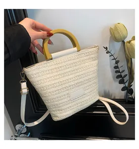 Détail du sac seau en paille tressée montrant la texture, la poignée et la bandoulière