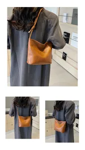 Detail of brown vintage suede bucket bag featuring embossed logo and slim shoulder strap