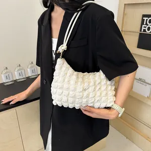 Détail du sac bulle blanc cassé avec texture plissée douce et anneau métallique sur la bandoulière