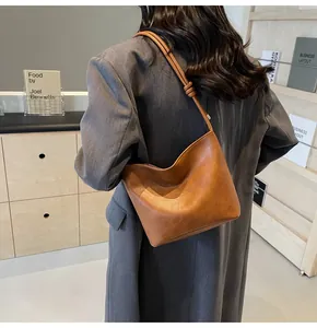 Brown faux leather shoulder bag with embossed text and decorative knot detail