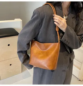 Close-up of brown suede bucket bag featuring embossed text and knotted strap detail