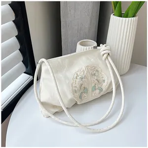 Dettaglio borsa beige stile orientale con ricami raffinati e una texture plissettata