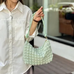Gros plan sur la texture gaufrée vert clair et les détails du sac à bandoulière