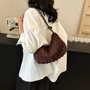 Détail d'un sac hobo marron foncé à texture bulle avec bandoulière en cuir nouée