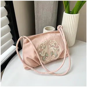 Dettaglio della borsa in raso rosa con eleganti ricami floreali in stile cinese tradizionale