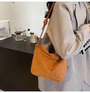 Detail of caramel suede bucket bag featuring fashion in sunday embossing and knotted strap