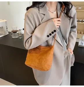 Caramel suede bucket bag detail with embossed lettering and shoulder strap knot