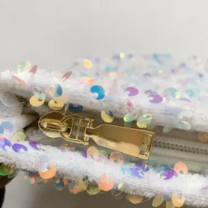 Detail of shimmering iridescent sequins and high-quality gold metal zipper on white bag