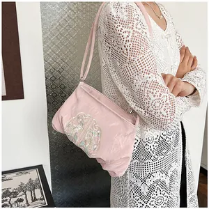 Dettaglio ravvicinato della borsa in raso rosa con eleganti ricami floreali