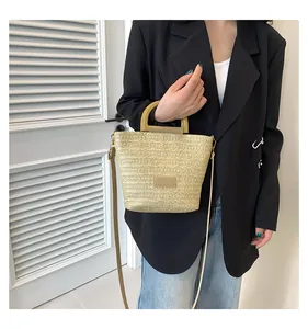 Détail du sac seau en paille tressée avec poignée ronde en bois et bandoulière