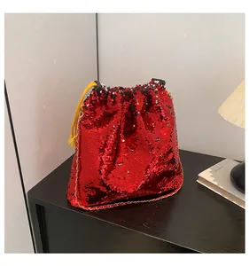 Detail view of red sequin bucket bag with gold chain strap and yellow tassels