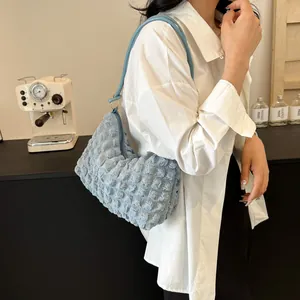 Vue latérale du sac à bandoulière bleu clair à bulles porté par un mannequin en café