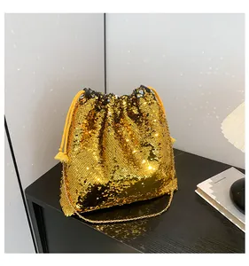 Detail of gold sequin bucket bag featuring drawstring closure and elegant chain strap
